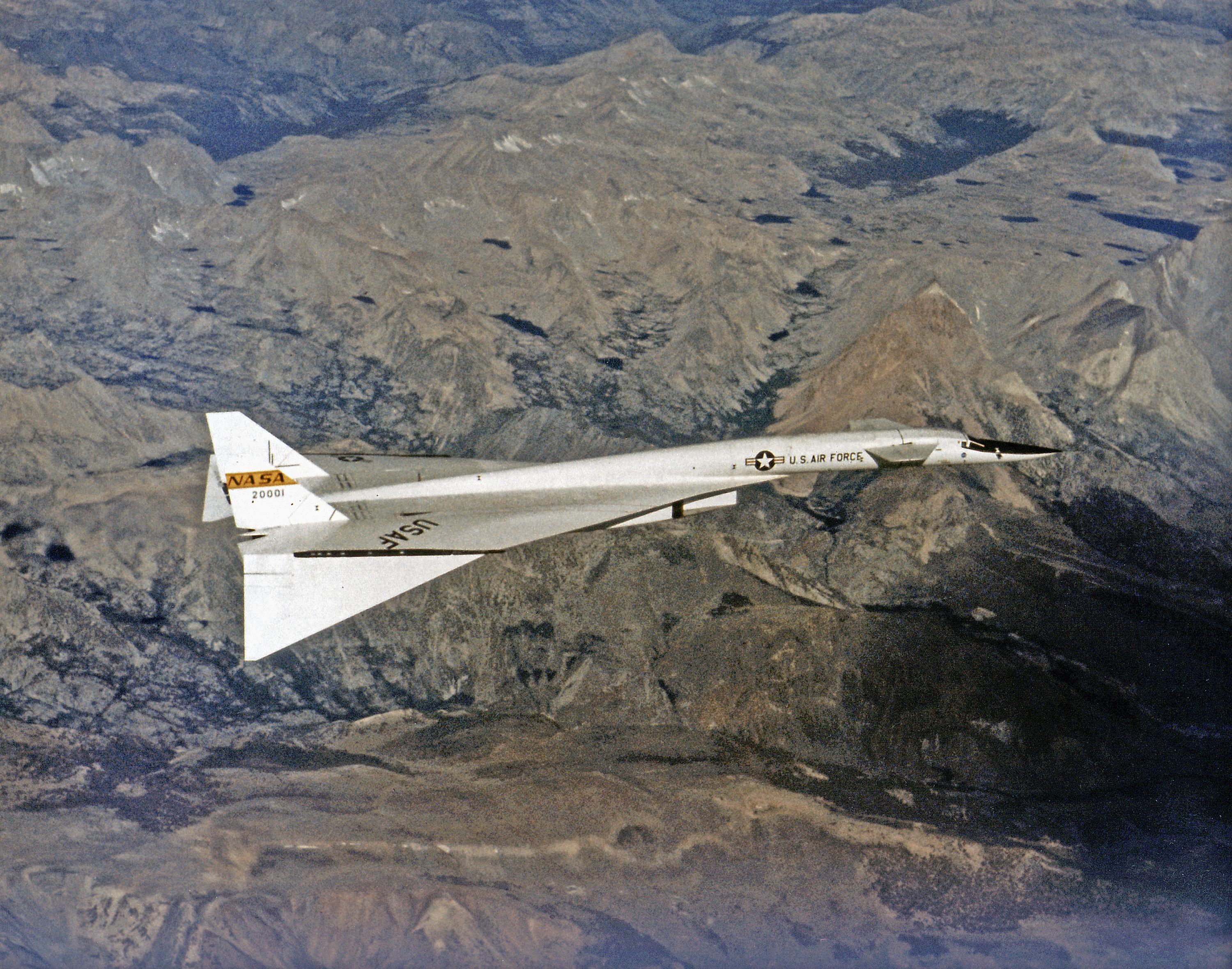 NASA Flight Research Center XB-70A No. 1 in cruise over mountains, white delta wing with wingtips drooped